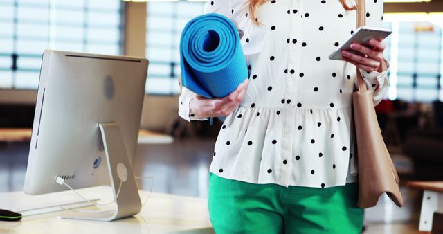 Woman holding yoga mat at office with smartphone - Download Free Stock Images Pikwizard.com