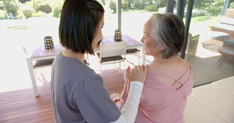 Physiotherapist assisting senior woman with shoulder exercise therapy