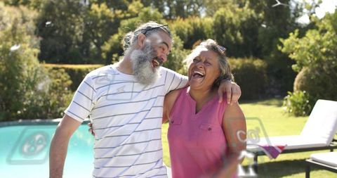 Mature couple laughing poolside enjoying sunlit backyard afternoon and affectionate moment