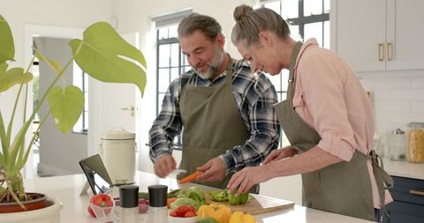 Senior Couple Preparing Meal with Tablet Guide in Bright Kitchen