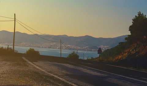 Scenic Coastal Road During Sunset with City Skyline View