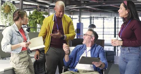 Diverse team collaborating in modern open-plan office using tablet and taking notes