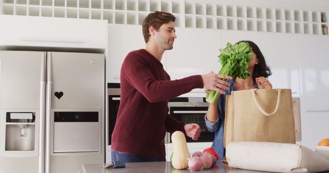 Image of happy diverse couple unpacking groceries in kitchen. Love, relationship and spending quality time together concept.