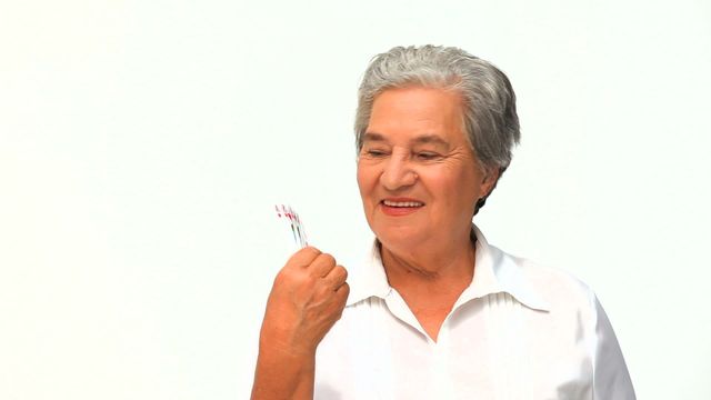 Woman holding and looking at playing cards, likely having a moment of victory or pleasure from a game. Perfect for use in topics related to senior lifestyle, leisure activities, happiness in older age, and leisure and hobby-related content.