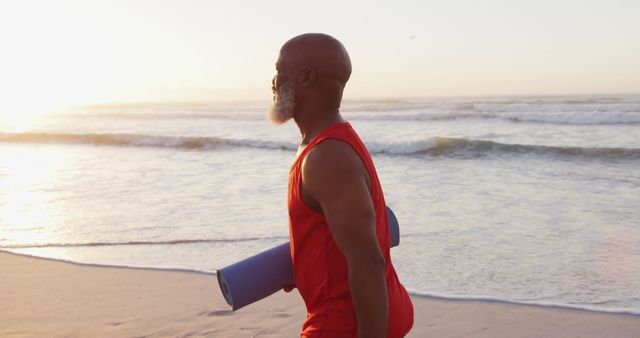 Senior Man Walking on Beach with Yoga Mat at Sunrise - Download Free Stock Images Pikwizard.com