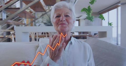 Senior woman sending virtual kiss during online celebration with neon growth chart overlay