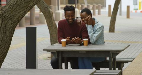 Couple Enjoying Coffee and Smartphone Outdoors