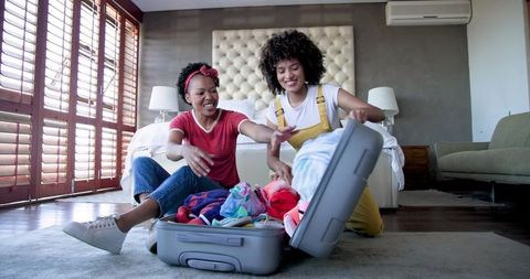Happy Couple Preparing Suitcase for Vacation in Bright Bedroom