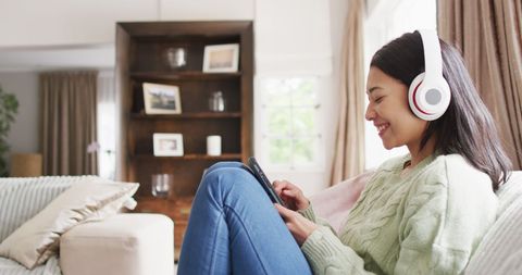 Biracial Woman Listening to Music on Headphones at Home