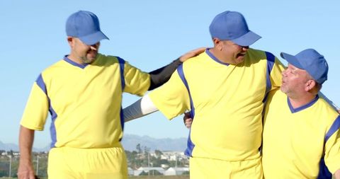 Celebrating teammates linking arms in yellow jerseys and blue caps on baseball field