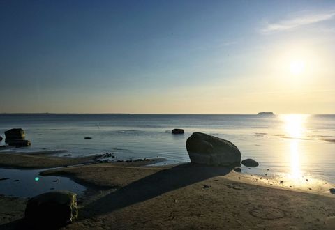 Serene Sunrise Over Calm Seashore with Rocky Beach