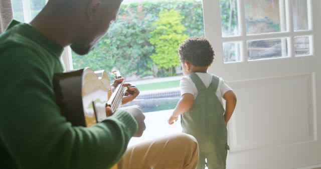 Father Playing Guitar Watching Child in Overalls by Doorway - Download Free Stock Images Pikwizard.com