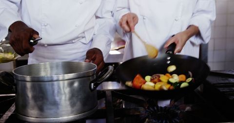 Chefs Skillfully Preparing Dishes Together in Professional Kitchen