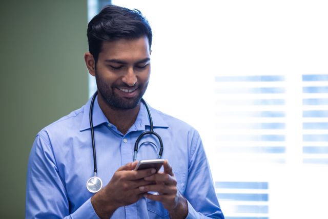 Doctor text messaging on mobile phone at the hospital