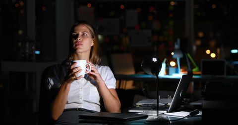 Businesswoman reflecting late at night in modern office