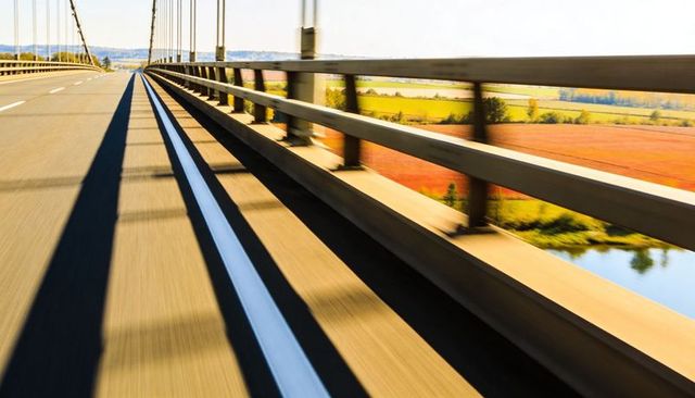 Racing Along Bridge Motion Blurred Roadway with Leading Lines Guardrail Suspension Cables