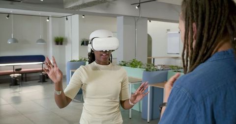 African American woman testing VR headset and gesturing in modern office collaboration