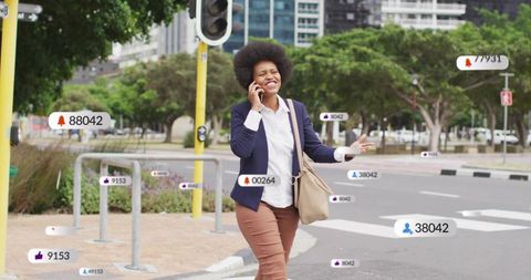 Professional woman walking and talking on phone at urban crosswalk with notifications
