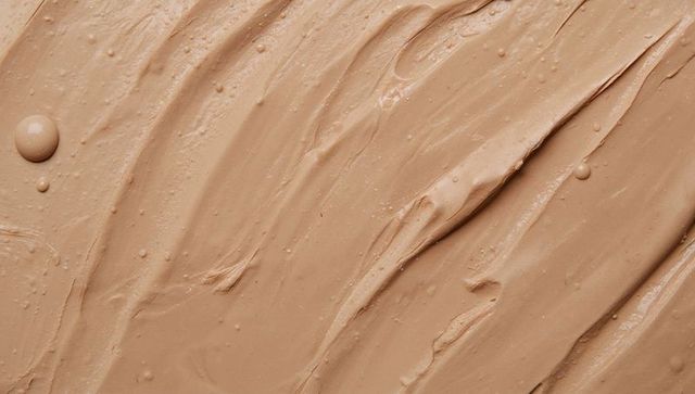 Beige foundation spreading with spatula strokes, glossy dollop and micro bubbles