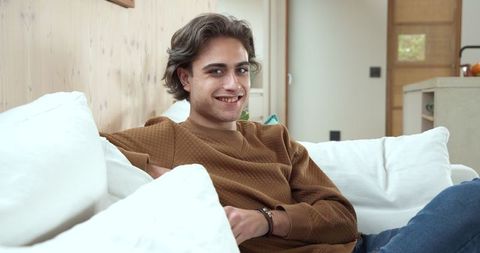 Relaxed woman in cozy living room wearing brown sweater into camera