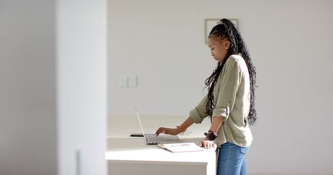 Young Woman with Long Braided Hair Using Laptop at Home Desk