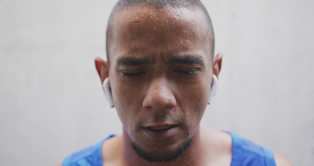 Portrait of sweaty biracial sports man with eyes closed wearing blue tshirt and earphones in city - Download Free Stock Photos Pikwizard.com