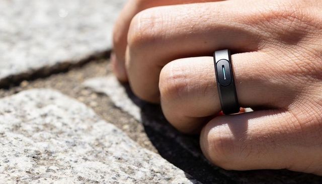 Matte black smart ring on resting right hand over sunlit granite surface for wearable tech