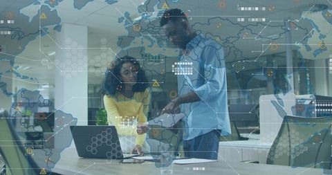 Business professionals collaborating over laptop and documents with global data map overlay