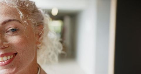 Cheerful Woman with Curly Hair Smiling in Office Hallway