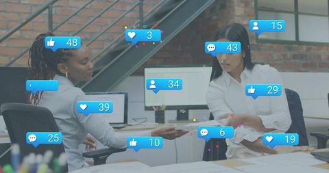 Collaborating women exchanging documents in modern office with social media notifications