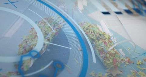 Spilling Glass Tubes Releasing Multicolored Confetti on Glossy Tabletop with HUD Rings