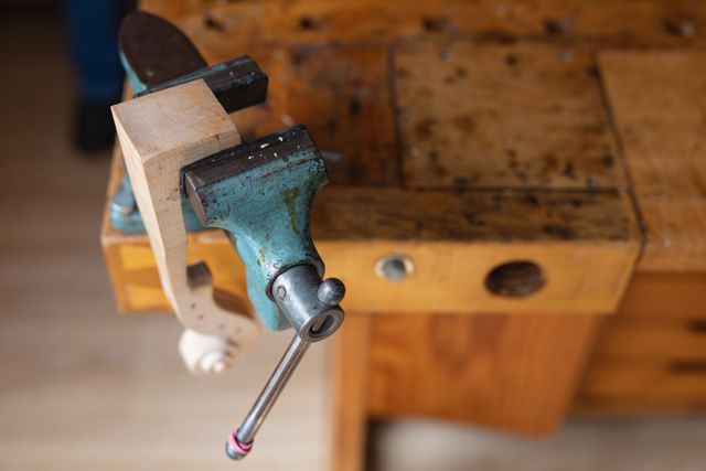 High angle view  showing a tool belonging to a luthier, a kind of vise used in violin making, clamped to the wooden workbench in the workshop.