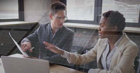 Business professionals collaborating over laptop and paperwork during office meeting