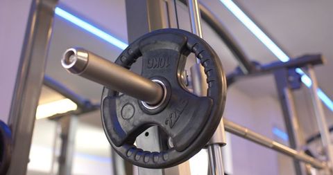 Close-up showing 10kg rubber-coated weight plate resting on chrome bar in gym rack