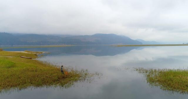A person stands by a serene lake, with copy space - Download Free Stock Photos Pikwizard.com