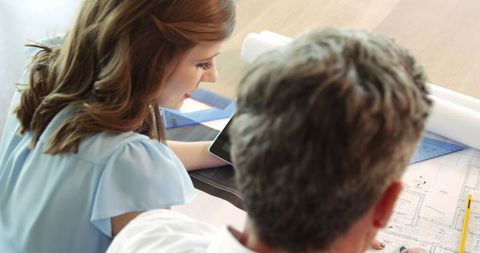 High Angle View of Colleagues Discussing Office Blueprint