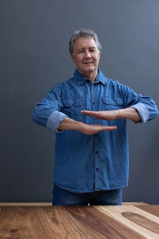 Senior Man Contemplating Wood Grain with Balanced Gesture