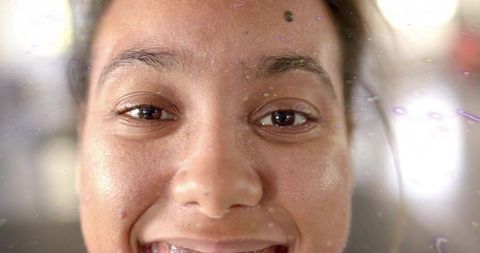 Close-up smiling woman with film droplets and purple lens flare, natural light portrait