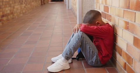 Child Sitting Alone at School with Face Buried in Arms