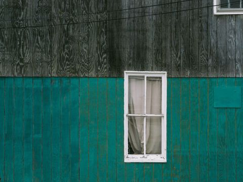 Weathered Teal Siding with Vintage White Window and Gray Wood Paneling, Minimal Facade