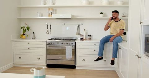 Man Enjoying Conversation Seated on Modern Kitchen Counter