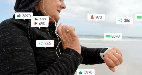 Active senior woman engaging with smartwatch technology at beach