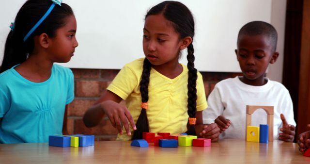 Three young children of different ethnicities are actively playing and collaborating with colorful wooden blocks. Ideal for use in educational content, children's activities, and diversity inclusion promotions. Appeals to themes of early childhood development, teamwork, and creative learning in school or classroom settings.