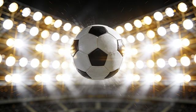 Flying classic black and white soccer ball under stadium floodlights with motion spray