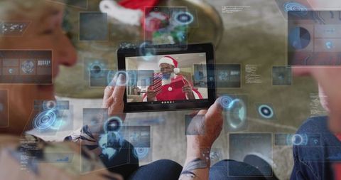Seniors holding tablet video calling santa with augmented reality holiday interface