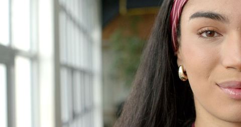 Sunlit serene portrait showing woman wearing maroon headband and gold hoop earring
