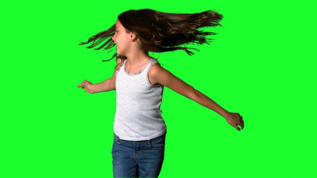 A young girl is captured mid-twirl against a vibrant green background, with her hair flying in motion. Her joyful and carefree expression embodies the essence of childhood fun. This image can be used to symbolize energy, happiness, and childhood in marketing campaigns, educational materials, or advertisements focused on children's products.