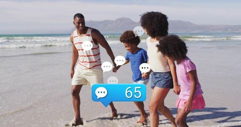 Family of four walking on beach holding hands with social media chat notification 65
