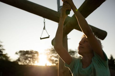 Boy climbing playground equipment at sunset adventure