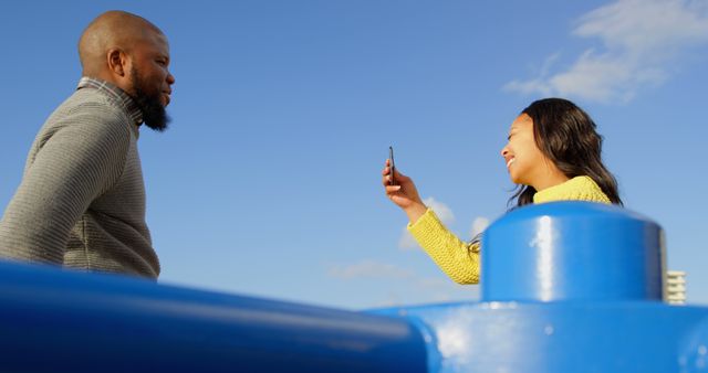 Smiling woman with smartphone taking picture of man outdoors - Download Free Stock Images Pikwizard.com